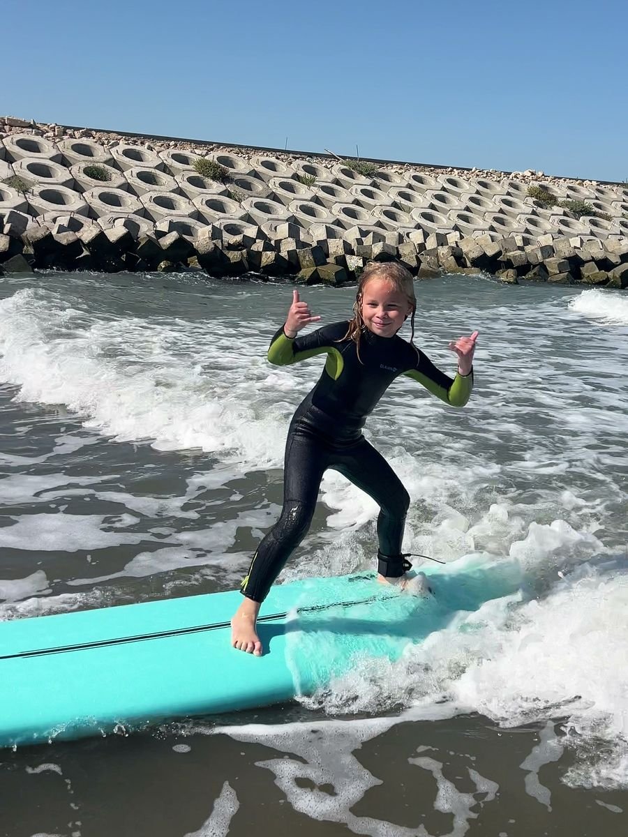 A young Surf Sea Breeze student riding a surfboard in the sea